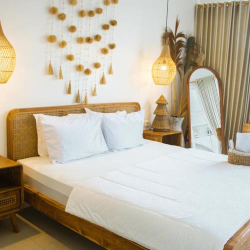 une chambre avec un lit avec des draps blancs et un miroir dans l'établissement Dry Villa, à Jarakan