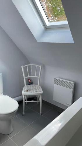 une salle de bain avec des toilettes, une chaise et une fenêtre dans l'établissement Comfortable house - Le Penty des Grands Champs, à Combrit