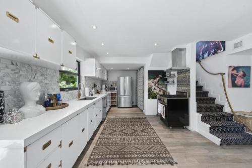 a kitchen with white cabinets and a staircase in the background at The Waterhouse- Amazing Villa With Infinity Pool in Miami