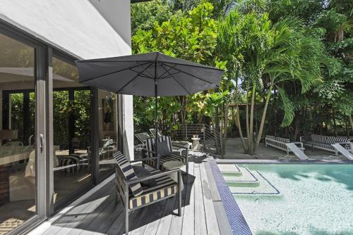 a patio with chairs and an umbrella next to a pool at The Waterhouse- Amazing Villa With Infinity Pool in Miami