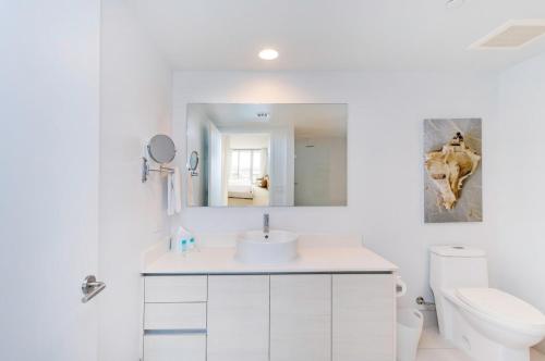 Un baño blanco con lavabo e inodoro. en 2 Bed 2 Bath With Amazing Bay View And Luxury Pool, en Hallandale Beach