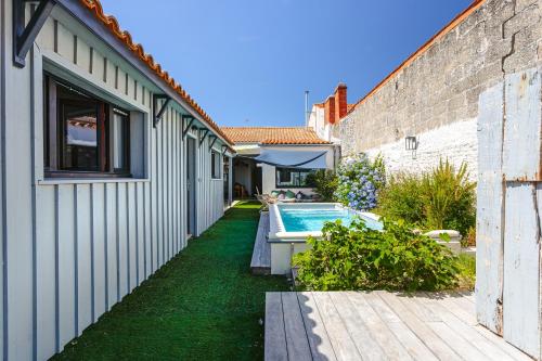 une cour avec une piscine à côté d'un bâtiment dans l'établissement Maison 4 chambres avec piscine, au Château-dʼOléron