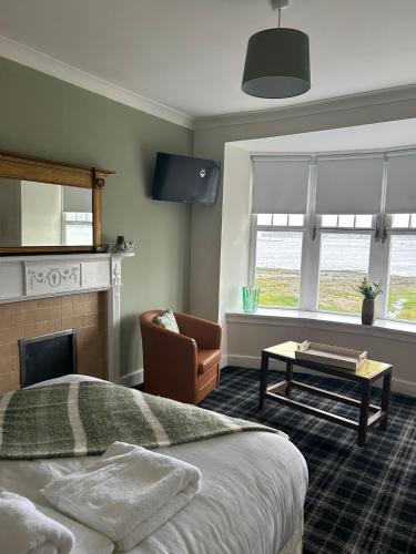 a bedroom with a bed and a chair and a fireplace at The Rhu Inn in Rhu