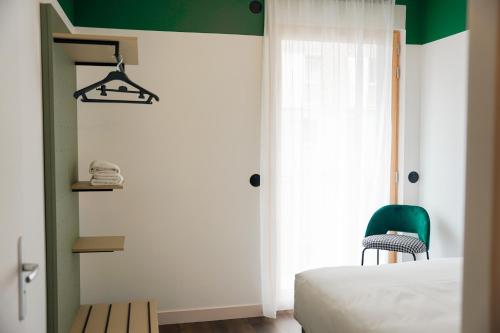 a bedroom with a bed and a green chair at All Suites Appart Hôtel et Hôtel - Paris 13 - Porte d'Italie in Paris