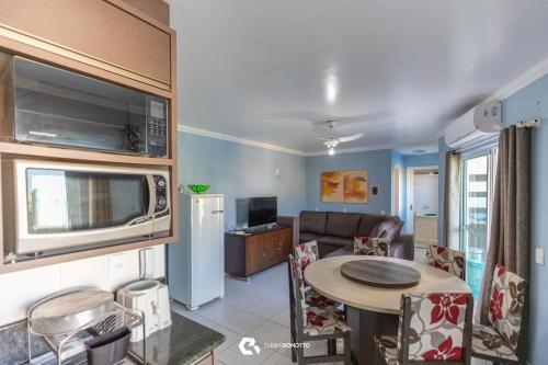 eine Küche und ein Wohnzimmer mit einem Tisch und einer Mikrowelle in der Unterkunft 150m do mar! Cobertura Duplex com Piscina Privada in Bombinhas