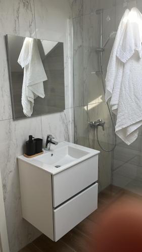 a white bathroom with a sink and a mirror at Apartament Giroc in Fratelia