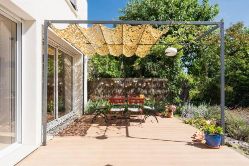 a patio with tables and chairs under a pergola at La Maison Château d'Eau : piscine pour 6/8 pers in Saint-Benoît