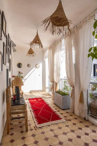 un soggiorno con tende bianche e un tappeto rosso di Riad El Jadide a Marrakech