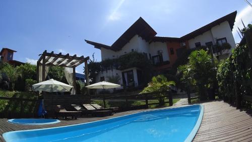 a swimming pool in front of a house at Vila Tamú in Praia do Rosa