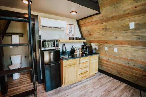 a kitchen with a black refrigerator and wooden walls at Starlight Haven at Weiss Lake in Gaylesville