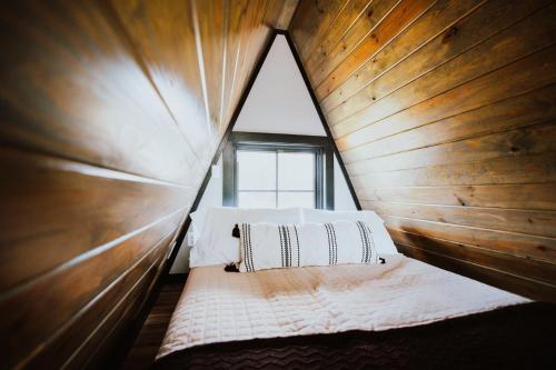 a bed in a wooden room with a window at Starlight Haven at Weiss Lake in Gaylesville