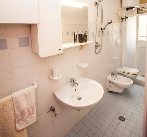 Un baño blanco con lavabo e inodoro. en Quiet little villa by the seaside in Rosolina Mare, en Rosolina Mare