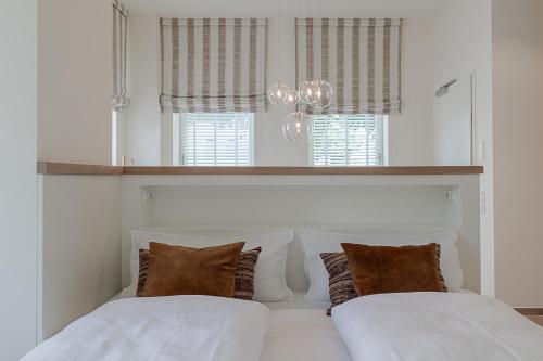 a bedroom with two white beds and two windows at Apartments Hotel Stadt Hamburg in Westerland (Sylt)