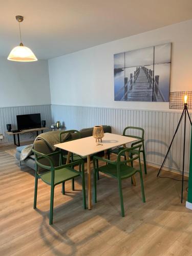 une salle à manger avec une table et des chaises vertes dans l'établissement Rue de la paix, à Mont-de-Marsan