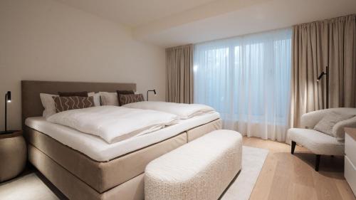 a bedroom with a large white bed and a chair at Apartments Hotel Stadt Hamburg in Westerland (Sylt)
