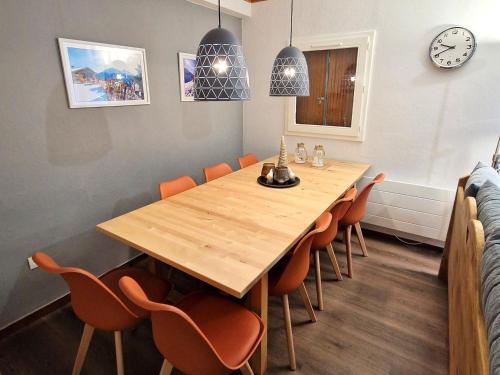 une salle à manger avec une table en bois et des chaises orange dans l'établissement Appartement cosy 6/8 pers, Valfréjus, près pistes et télécabines - FR-1-265-343, à Modane