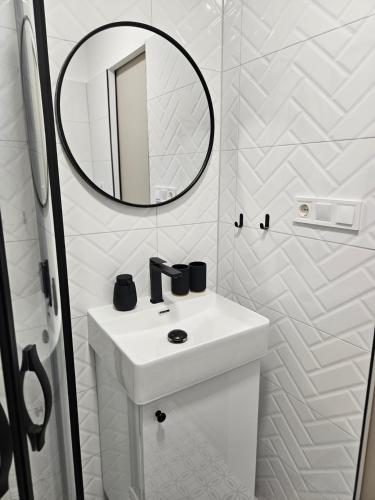 a white bathroom with a sink and a mirror at D422Apartman in Dunaújváros