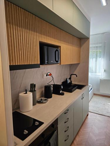 a kitchen with a counter top with a tv on the wall at D422Apartman in Dunaújváros