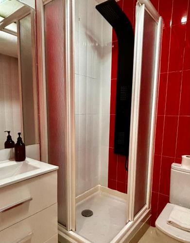 a shower in a bathroom with red tile at CHUECA Apartamentos Noxi in Madrid