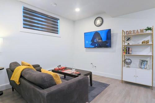 a living room with a couch and a clock on the wall at Cozy 1-Bedroom Basement Suite in Rosewood in Saskatoon