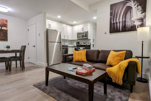 a living room with a couch and a table and a kitchen at Cozy 1-Bedroom Basement Suite in Rosewood in Saskatoon