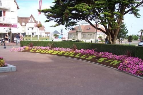 a walkway with pink flowers in a park at Maison près de la mer , les plages du débarquement in Courseulles-sur-Mer