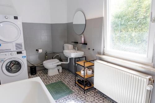 a bathroom with a toilet and a sink and a washing machine at Leopold's Apartments mit Garten und Vesteblick Mitten in Coburg in Coburg