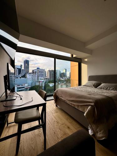 a bedroom with a bed and a desk and a window at Luxury Apartment in Roma Norte With Stunning Views in Mexico City
