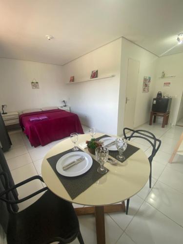 a table and chairs with a plate on it in a room at Refúgio das Ondas I Suítes perto da praia com conforto e self check-in in Bertioga