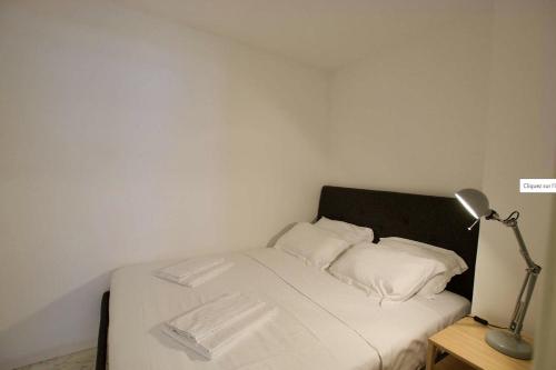 - un petit lit avec des draps blancs et une lampe dans l'établissement Beautiful apartment with Sea View / 21, à Beausoleil