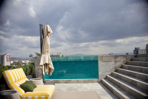 a swimming pool with a yellow chair and a umbrella at Luxury Apartment in Roma Norte With Stunning Views in Mexico City