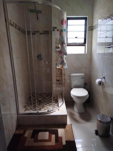 a bathroom with a shower and a toilet at Shalakwe Hills-Inn Guesthouse Kasane in Kasane