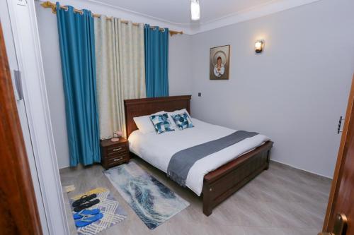 a bedroom with a bed with blue curtains at Yo House Muyenga in Muyenga 