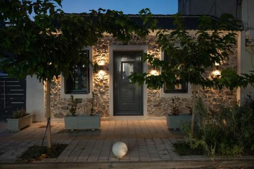 a stone house with a door and a tree at Centro Stone House in Tolo