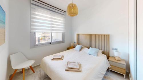 a bedroom with a bed and a chair and a window at Casa Virginia in Los Alcázares