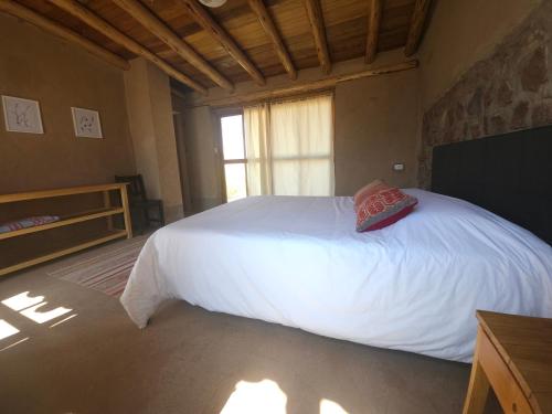 a bedroom with a white bed and a window at Pampachayoq - Mountain retreat in Urubamba