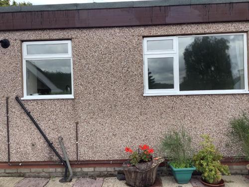 two windows on the side of a house with potted plants at Aqueduct apartment near Llangollen in Llangollen