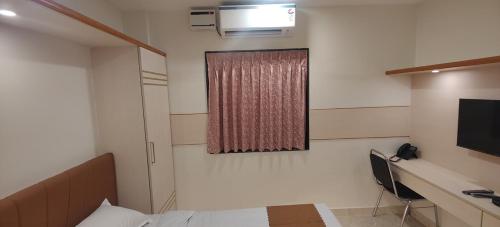 una stanza con un letto, una scrivania e una finestra di Nandhavanam A Business Class Residency a Chennai