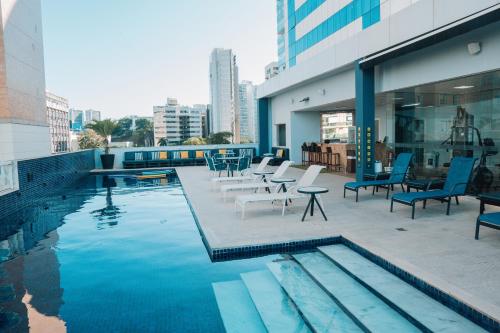 a pool with chairs and tables on a building at Golden Tulip Porto Vitória in Vitória