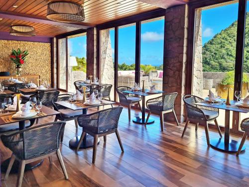a dining room with tables and chairs and windows at Coulibri Ridge in Soufrière