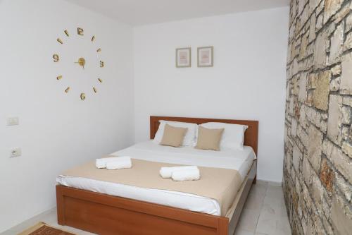 a bedroom with a bed and a clock on the wall at Stone House Berat in Dushnik