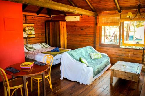 a bedroom with two beds and a table in a cabin at En calma in Punta Del Diablo