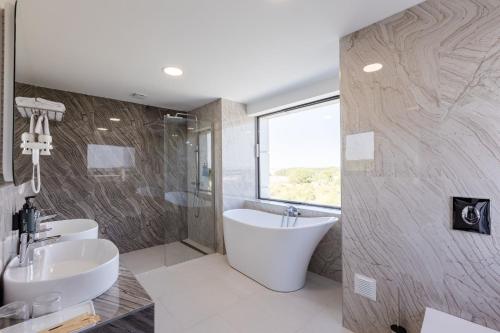 a bathroom with a tub and a sink and a shower at Ramada by Wyndham Bucharest Otopeni Airport in Otopeni
