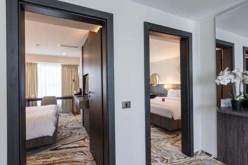 a hotel room with a corridor with two beds at Ramada by Wyndham Bucharest Otopeni Airport in Otopeni