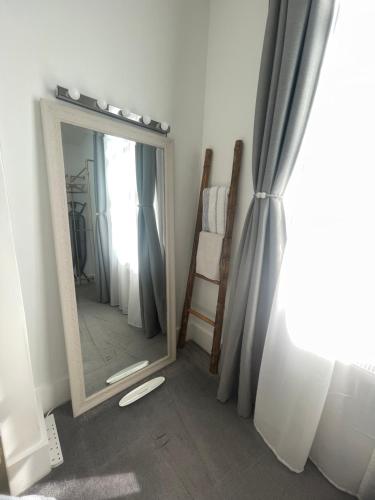 ロンドンにあるQueen bedroom in Maida Valeのカーテンのかかった部屋の隅にある鏡