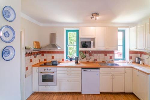 a kitchen with white cabinets and white appliances at Fara Bošín in Křinec