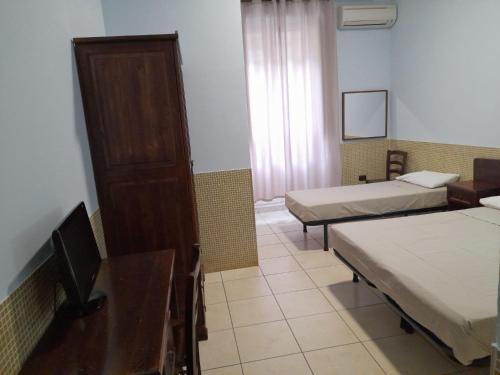 a room with two beds and a desk and a tv at Hotel Vittorio Veneto Napoli in Naples
