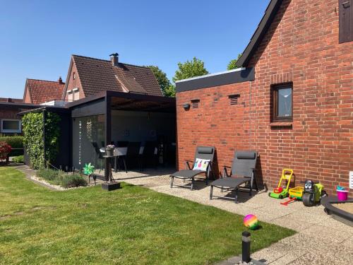a backyard with chairs and a brick building at Haus HERNA by fewo-plan WING120 Nähe Nordsee, Kreidesee Hemmoor und Naturpark Wingst in Oberndorf