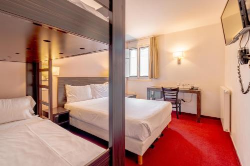 オルリーにあるGrand Hotel Séniaのベッド2台、デスク、鏡が備わる客室です。