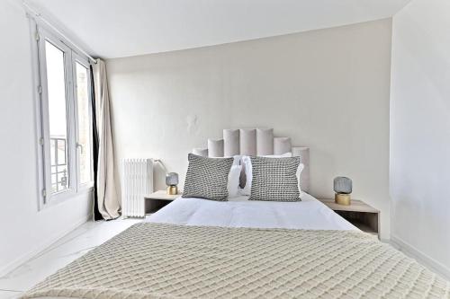 une chambre blanche avec un grand lit blanc avec des oreillers dans l'établissement Appartement conviviale et lumineux - III, à Gournay-sur-Marne